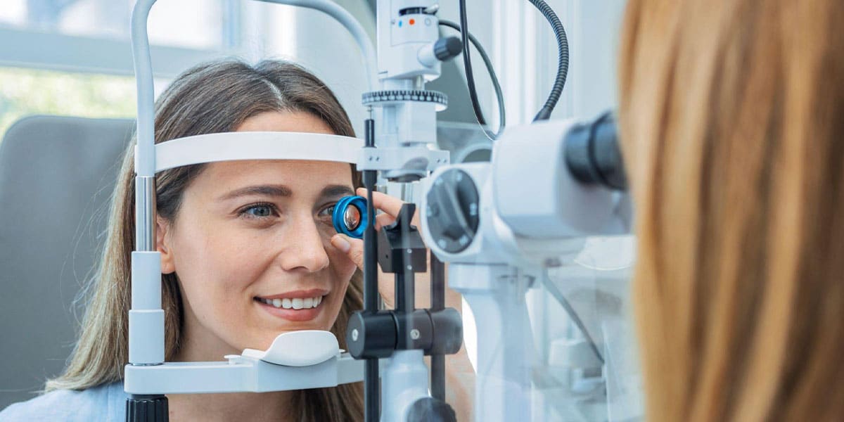 Mujer joven durante un examen ocular con un optometrista, mirando a través de un equipo de diagnóstico visual.